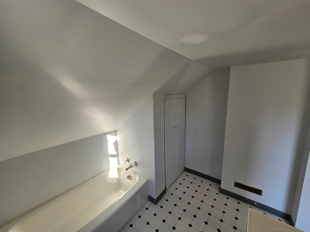 bathroom with a washtub and lofted ceiling