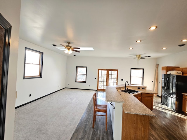 kitchen with a kitchen island with sink, sink, ceiling fan, and black fridge