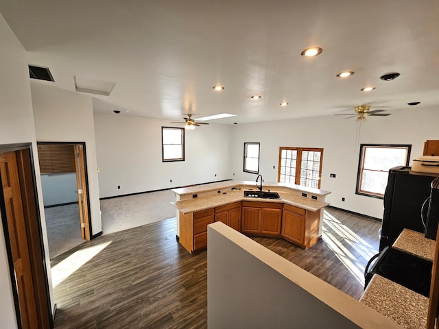 kitchen featuring an island with sink, lofted ceiling, sink, ceiling fan, and dark wood-type flooring