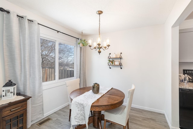 dining area featuring light wood-type flooring and an inviting chandelier