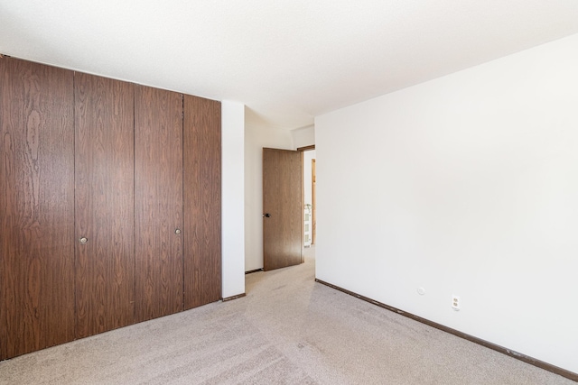 unfurnished bedroom featuring a closet and light carpet