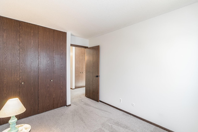 unfurnished bedroom with a closet and light carpet