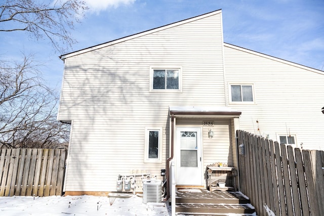 snow covered rear of property with central AC unit