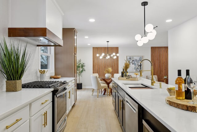 kitchen featuring decorative light fixtures, custom exhaust hood, sink, stainless steel appliances, and white cabinets