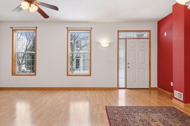 foyer entrance with ceiling fan, light hardwood / wood-style flooring, and a textured ceiling