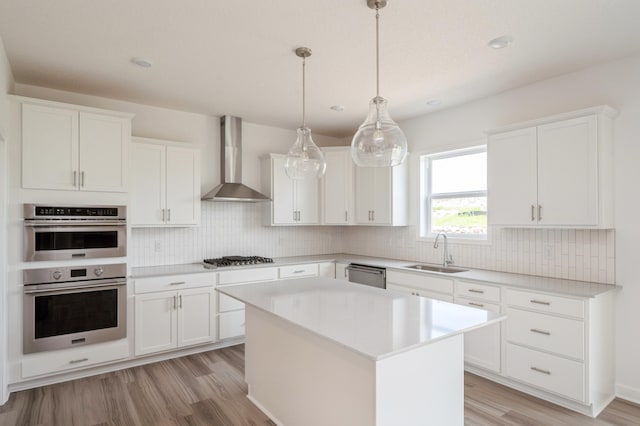 kitchen featuring wall chimney exhaust hood, a kitchen island, and white cabinetry