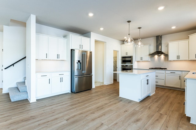 kitchen with white cabinets, appliances with stainless steel finishes, decorative light fixtures, and wall chimney range hood