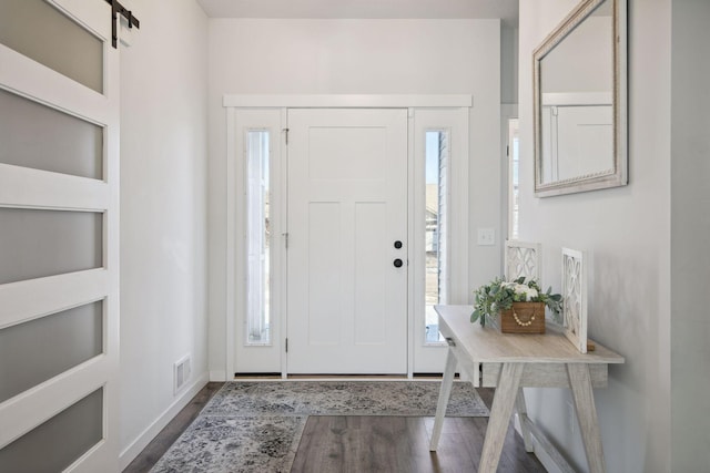 entrance foyer with a barn door, plenty of natural light, and hardwood / wood-style flooring