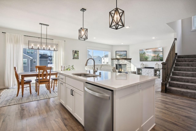 kitchen featuring a center island with sink, stainless steel dishwasher, sink, hanging light fixtures, and white cabinets