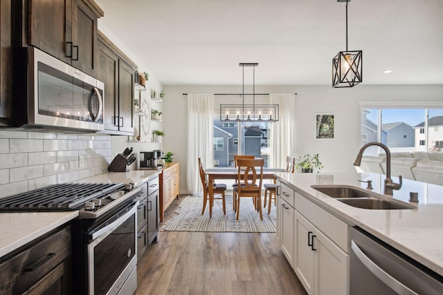 kitchen featuring appliances with stainless steel finishes, dark hardwood / wood-style floors, dark brown cabinets, pendant lighting, and sink