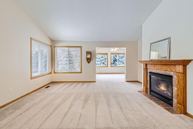 unfurnished living room with vaulted ceiling, a textured ceiling, a fireplace, and light carpet