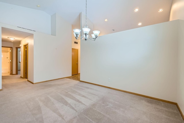 carpeted spare room with high vaulted ceiling and a chandelier