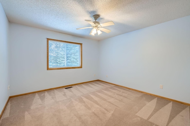 spare room with ceiling fan, a textured ceiling, and light carpet