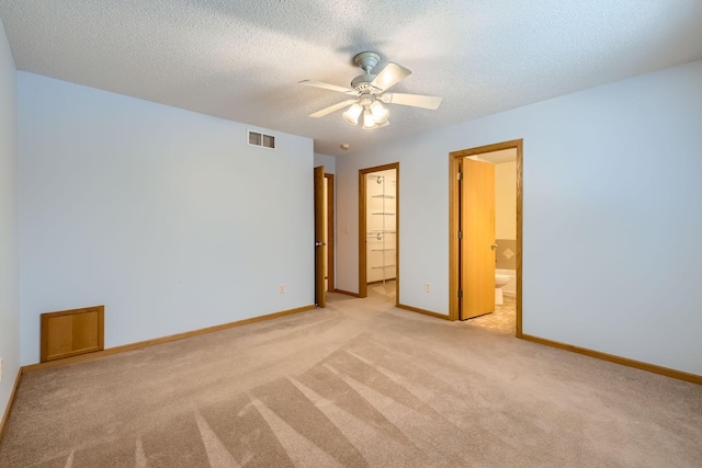 empty room featuring ceiling fan, a textured ceiling, and light carpet