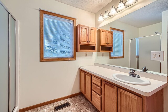 bathroom featuring vanity, plenty of natural light, a textured ceiling, and an enclosed shower