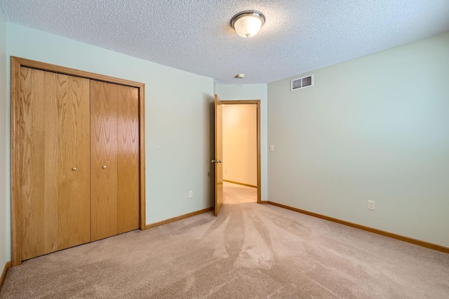 unfurnished bedroom with a closet, a textured ceiling, and light carpet