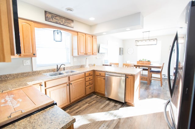 kitchen featuring black refrigerator, kitchen peninsula, pendant lighting, sink, and stainless steel dishwasher