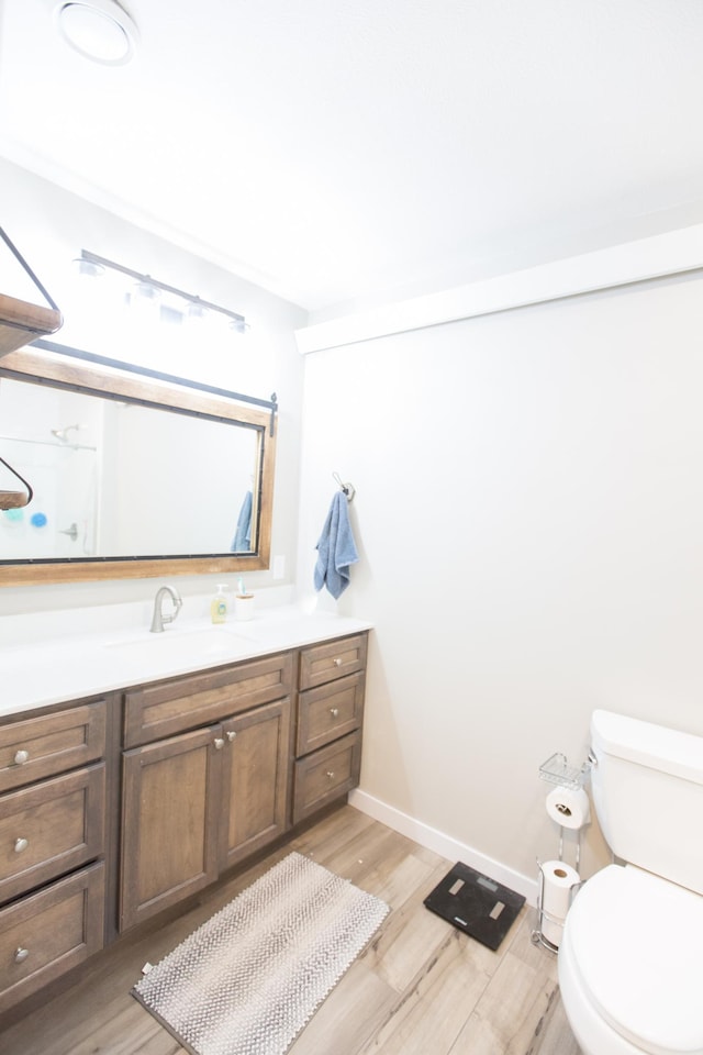 bathroom with toilet, wood-type flooring, and vanity