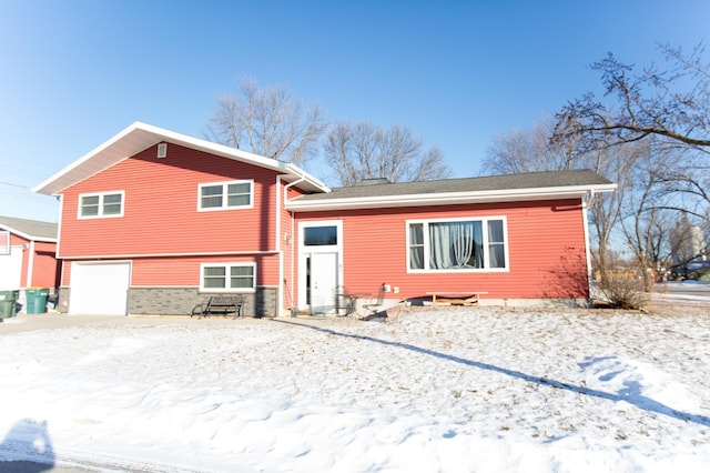 snow covered rear of property featuring a garage