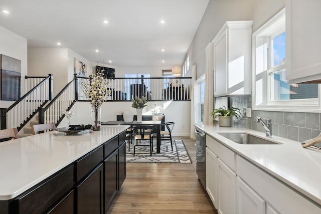 kitchen with hardwood / wood-style flooring, stainless steel dishwasher, white cabinetry, and sink