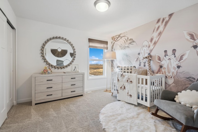 bedroom with a closet, light colored carpet, and a nursery area