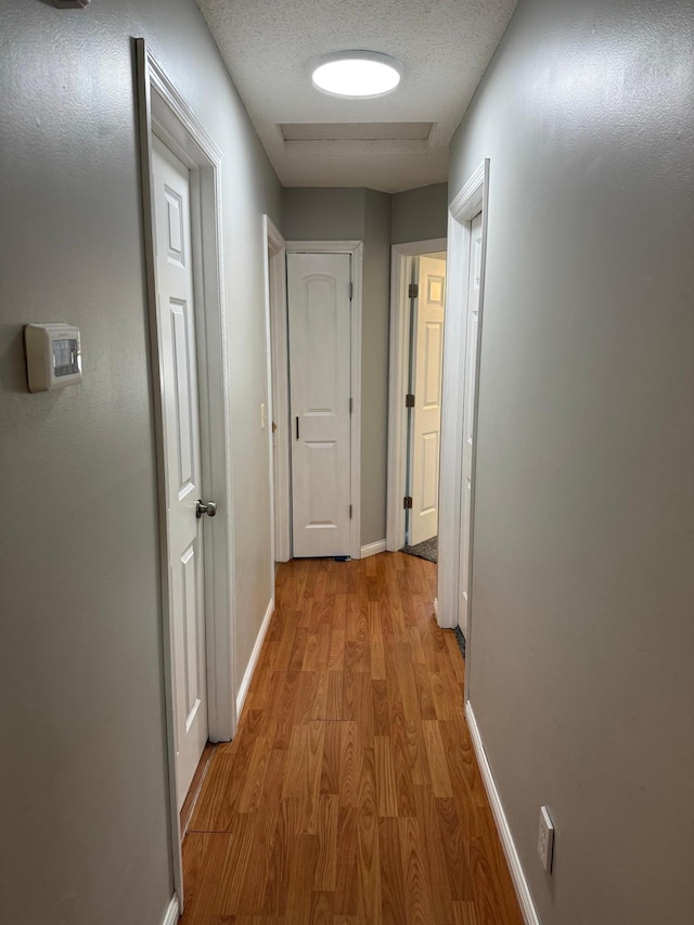 hall featuring a textured ceiling and light wood-type flooring