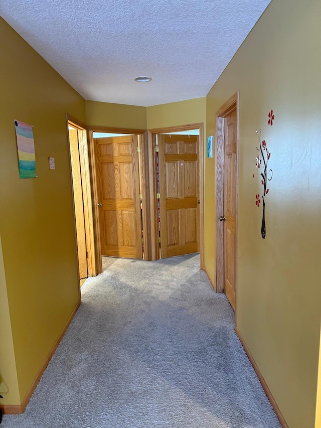 hallway with light colored carpet and a textured ceiling