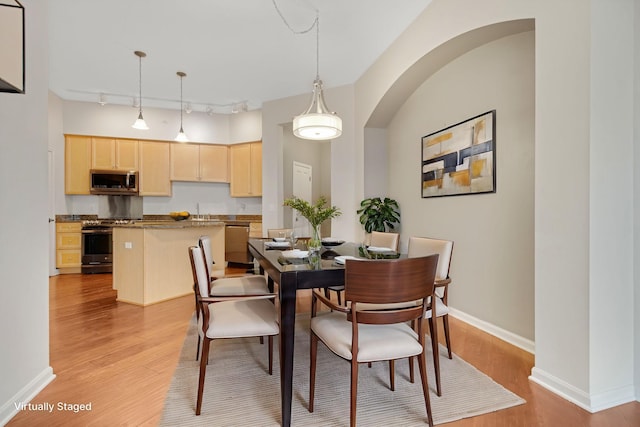 500 Grant St Unit 204, Minneapolis, MN 55404 - dining area featuring light wood finished floors, rail lighting, and arched walkways