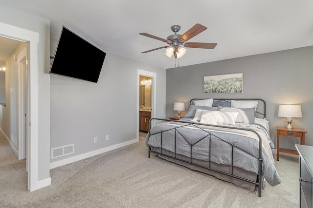 bedroom featuring ceiling fan, ensuite bathroom, and light colored carpet