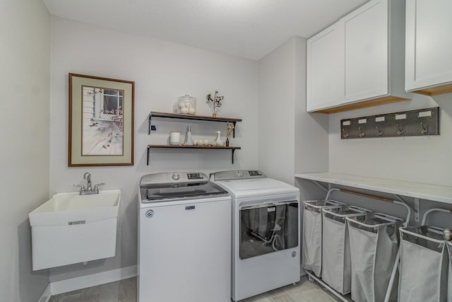 laundry room with cabinets, light hardwood / wood-style flooring, washing machine and clothes dryer, and sink