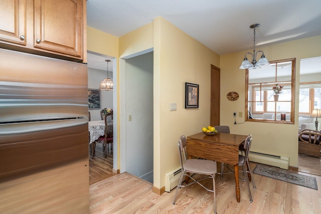 dining space with a notable chandelier, light wood-type flooring, and baseboard heating