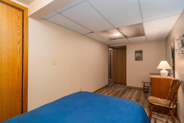 bedroom with hardwood / wood-style floors, a drop ceiling, and a closet