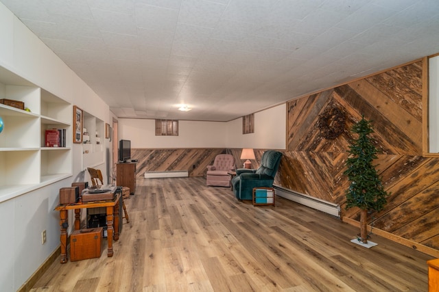 living room with built in shelves, baseboard heating, wooden walls, and hardwood / wood-style floors