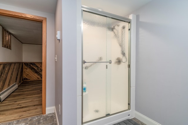 bathroom with baseboard heating, wood walls, and a shower with shower door