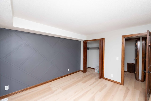 unfurnished bedroom with a closet, light wood-style flooring, and baseboards