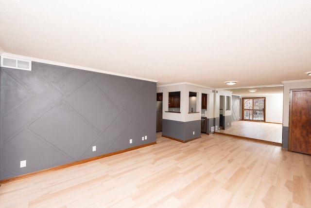 unfurnished room featuring light wood-type flooring, visible vents, ornamental molding, and a decorative wall