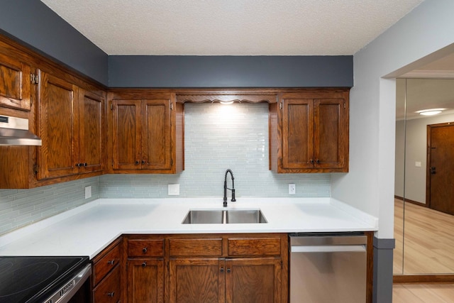 kitchen with a sink, stainless steel dishwasher, under cabinet range hood, and light countertops