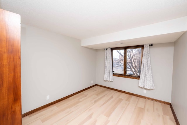 spare room with light wood-style flooring and baseboards