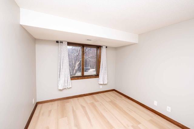 empty room featuring visible vents, baseboards, and light wood-style floors