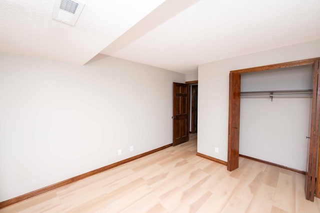 unfurnished bedroom featuring light wood finished floors, visible vents, a closet, and baseboards