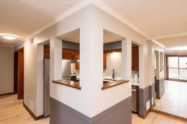 1720 3rd Ave S Unit 101, Minneapolis, MN 55404 - kitchen featuring a sink, light wood-type flooring, stainless steel appliances, under cabinet range hood, and crown molding