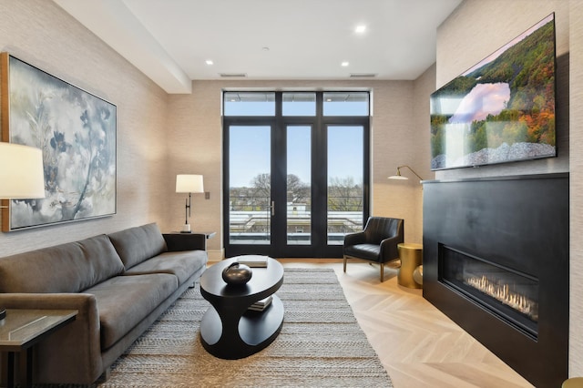 living room with a wall of windows, light parquet flooring, a large fireplace, and french doors