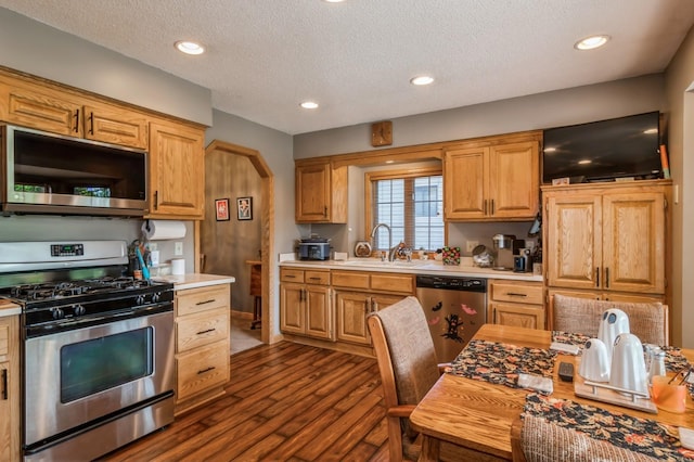 kitchen featuring a textured ceiling, sink, stainless steel appliances, and dark wood-type flooring