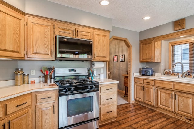 kitchen with a textured ceiling, sink, appliances with stainless steel finishes, and dark wood-type flooring