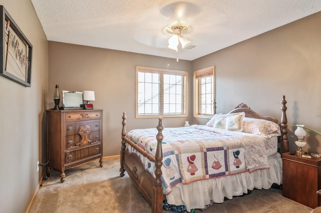 bedroom featuring a textured ceiling, light colored carpet, and ceiling fan