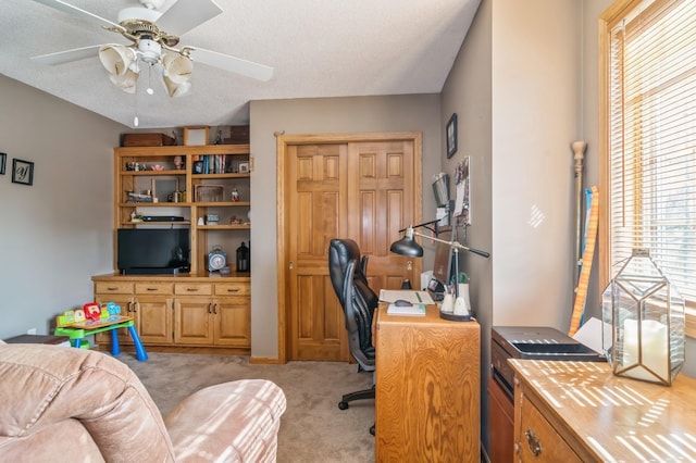 office space featuring a textured ceiling, light colored carpet, and ceiling fan