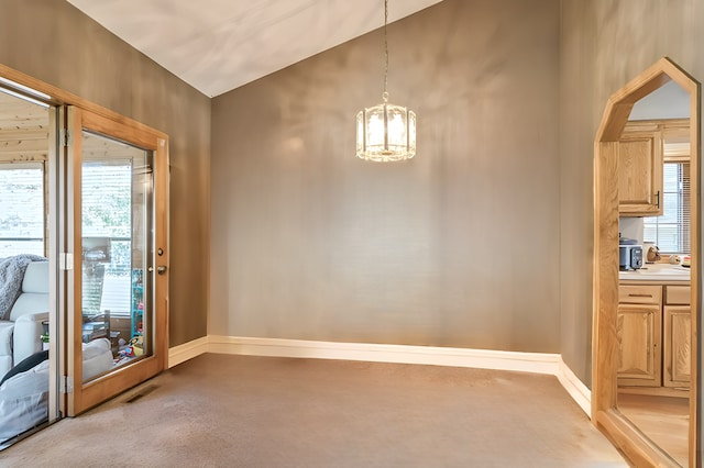 unfurnished dining area featuring carpet, a healthy amount of sunlight, lofted ceiling, and an inviting chandelier