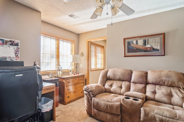 office area featuring light carpet, ceiling fan, and a textured ceiling