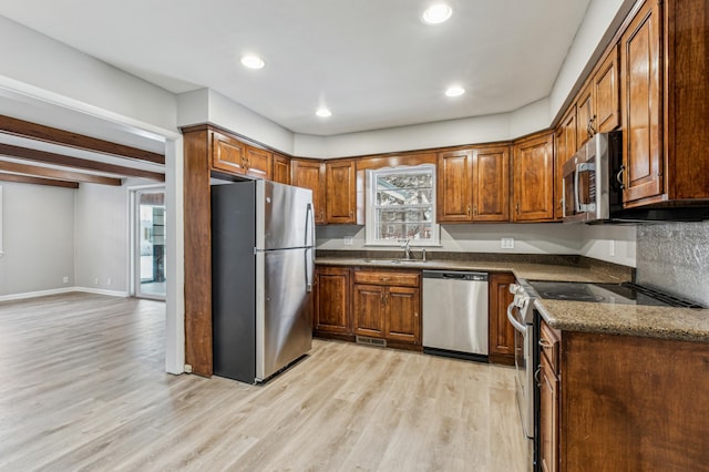 kitchen with stainless steel appliances, dark stone countertops, light hardwood / wood-style flooring, and plenty of natural light