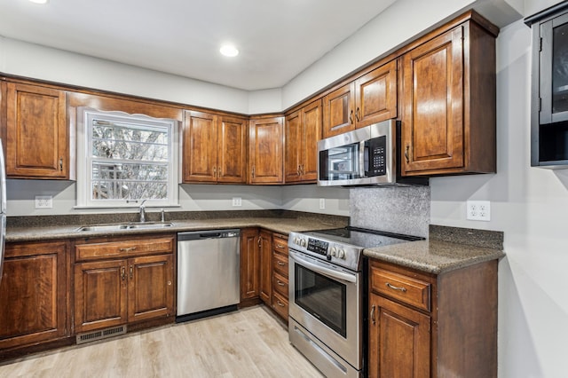 kitchen featuring stainless steel appliances, light hardwood / wood-style flooring, and sink